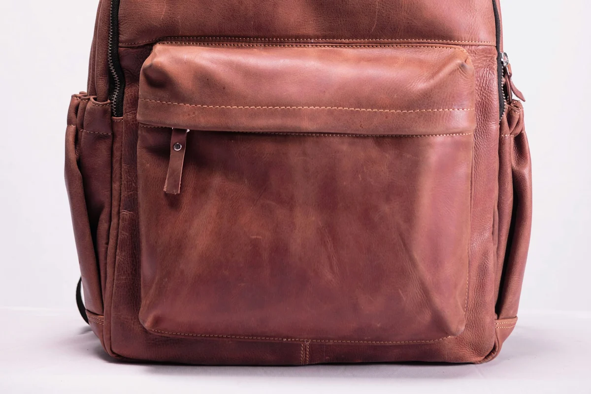 Checking a leather bag's seams and stitching to confirm it is real leather