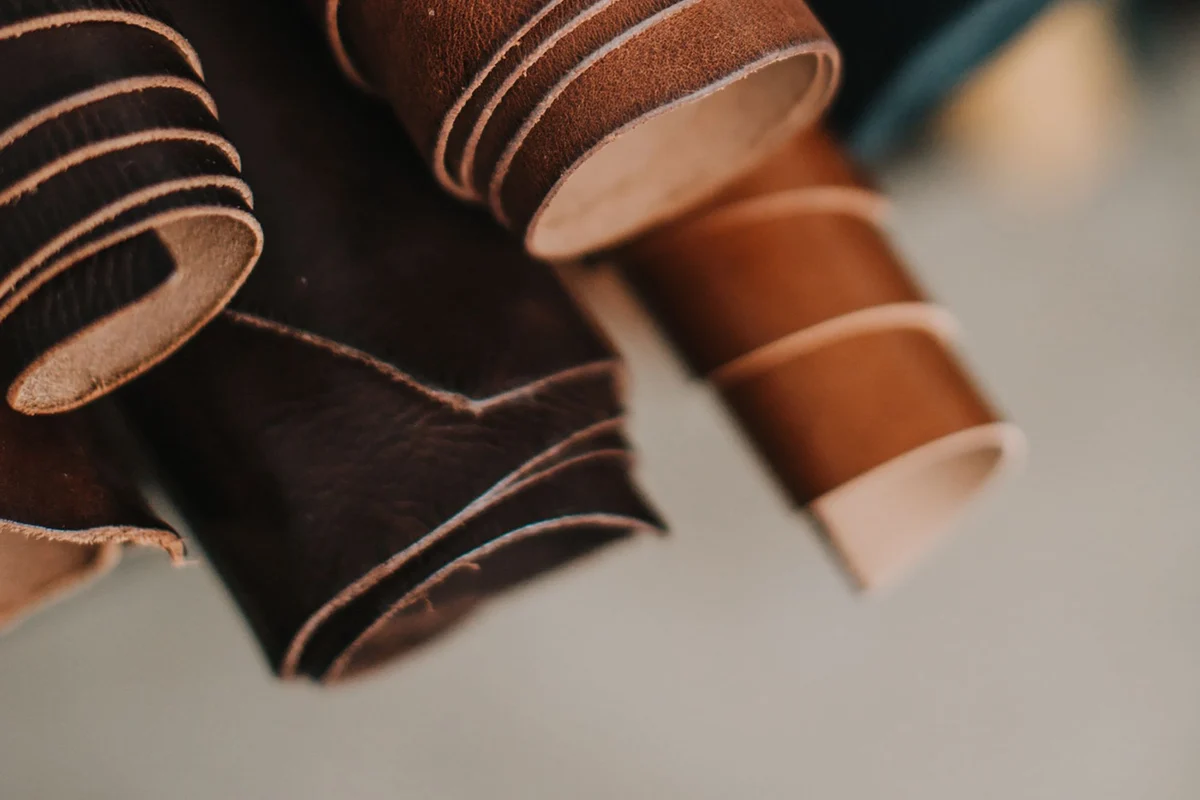 Rolled full-grain leather hides stacked, showing quality leather material