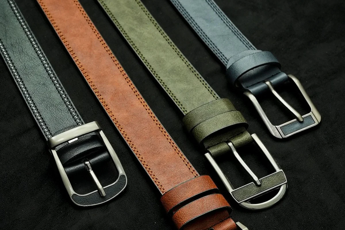 Four leather belts in tan, olive, grey and navy with silver buckles, showing different belt colours and widths